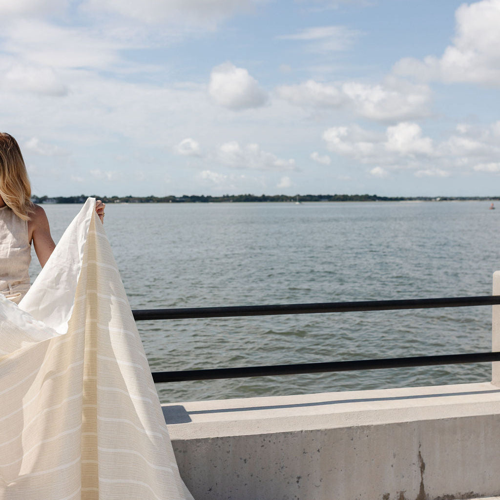 Image of the Charleston harbor with a woman holding Emily Daws fabric by the yard