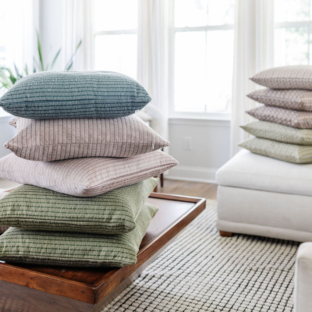 Stack of Emily Daws Jetty Cove pillow stacked in a bright living room, boutique woven textiles designed for Southern-inspired interiors.