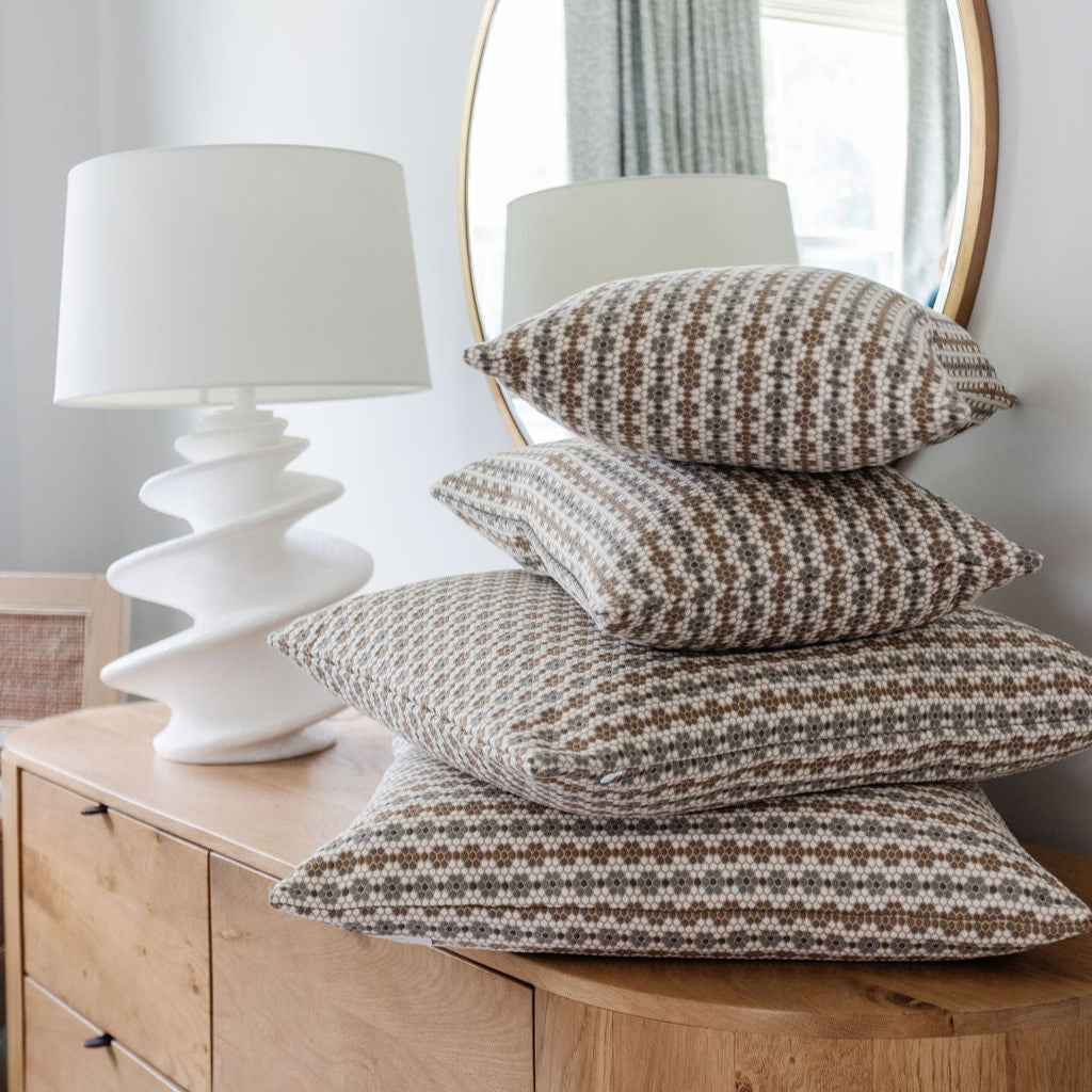 Stacked Emily Daws pillows in small-batch fabrics, styled to highlight bespoke textiles for interior designers.