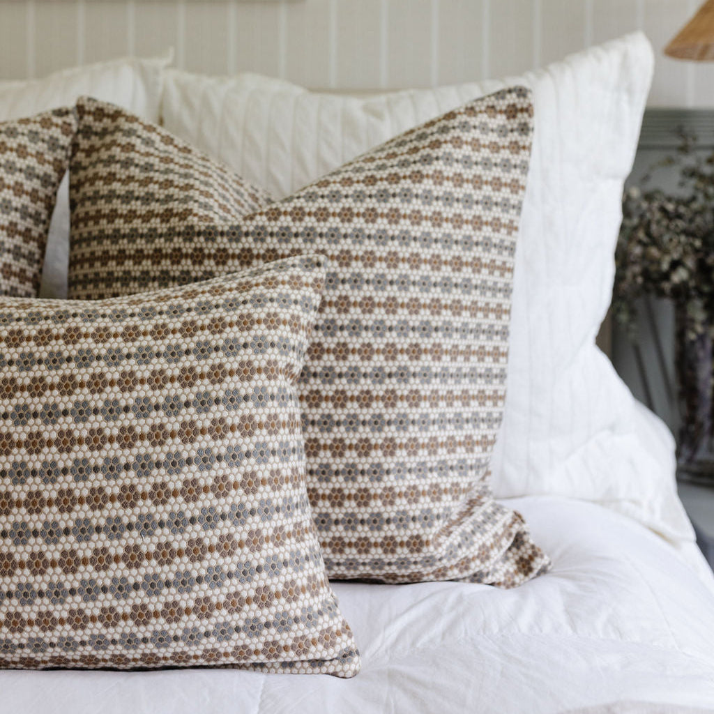 Decorative pillows by Emily Daws arranged on a bed, designed for bespoke interiors and Southern-inspired style.