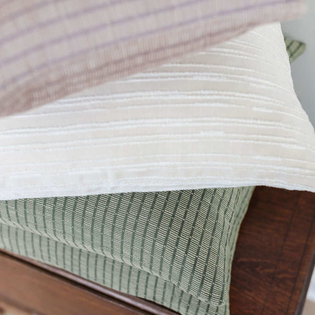 Boutique pillows from Emily Daws Textiles stacked to reveal layered texture and heirloom-inspired patterns.