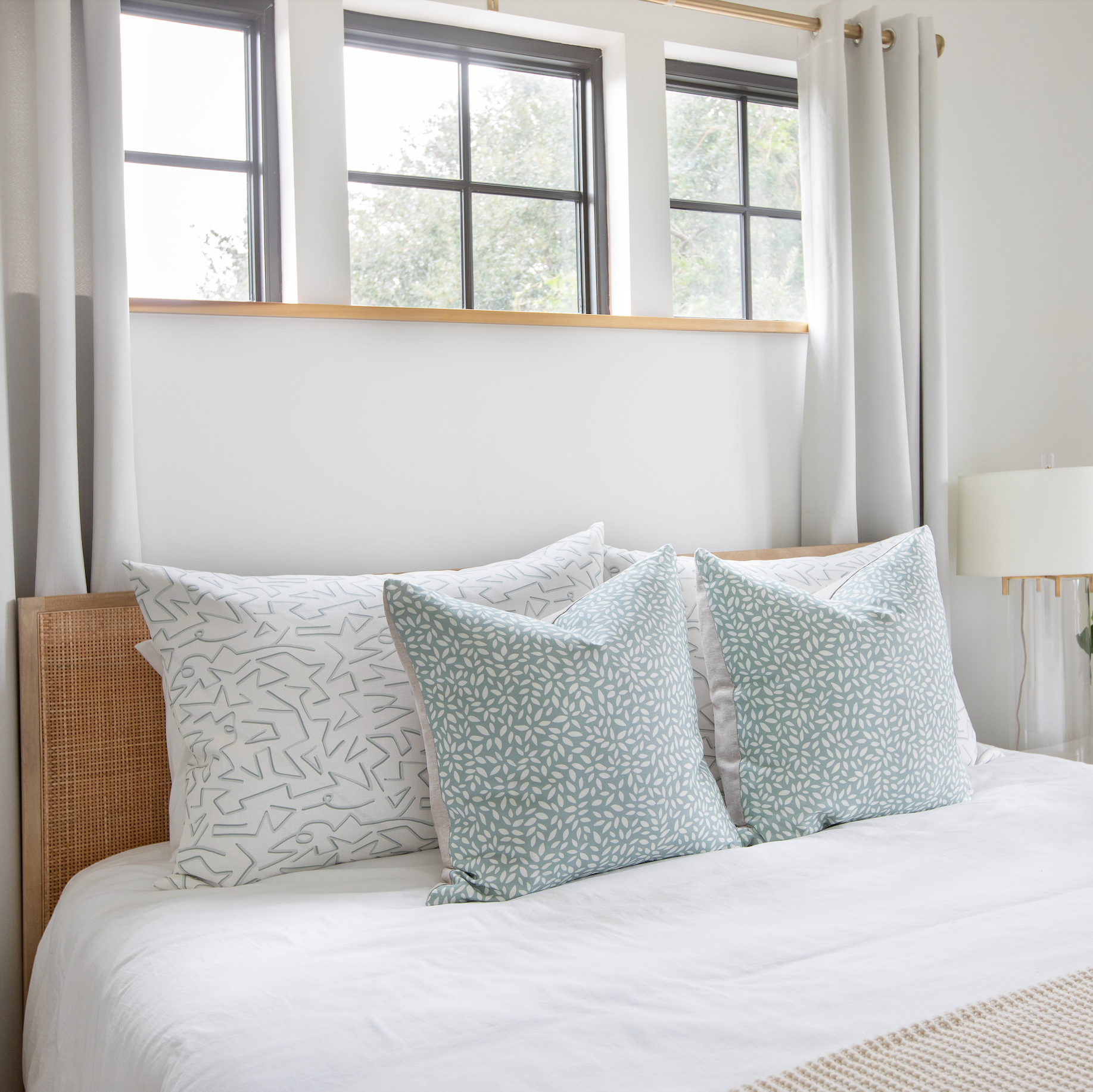 Emily Daws throw pillows layered on a bed, showcasing luxury textiles and heirloom-inspired patterns for designers.