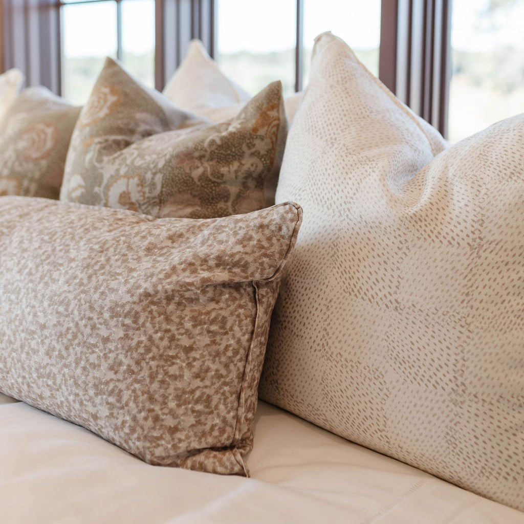 Emily Daws throw pillows layered on a bed, showcasing luxury textiles and heirloom-inspired patterns for designers.