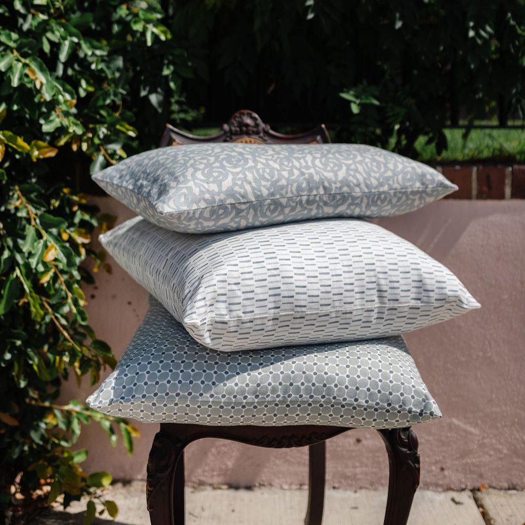 A trio of Emily Daws pillows stacked in soft neutral tones, created with small-batch fabrics for refined Southern homes.