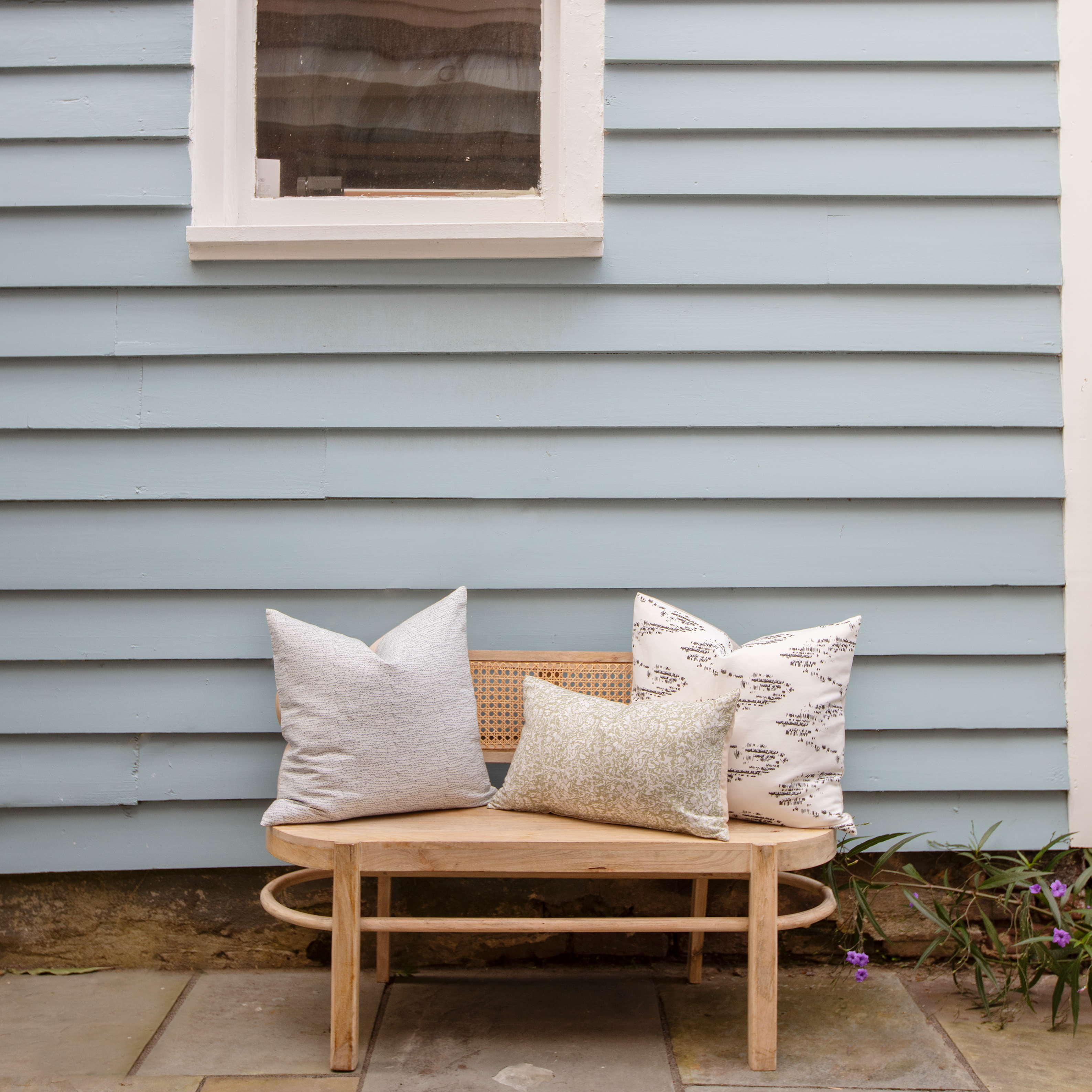 Estuary pillow styled by Emily Daws – placed on a cane chair in a Charleston sunroom