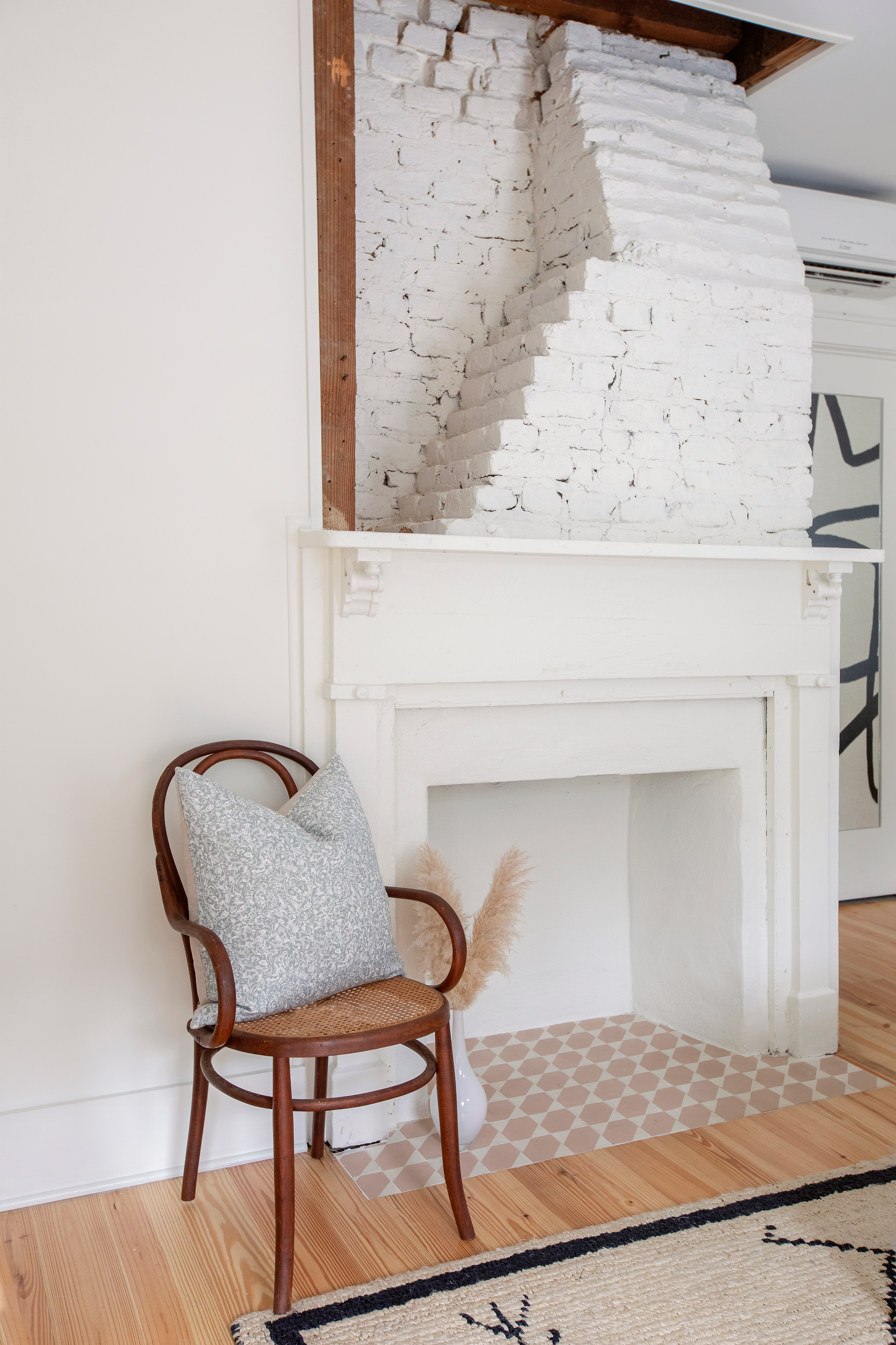 Estuary pillow in Artichoke styled by Emily Daws – placed on a cane chair in a Charleston sunroom
