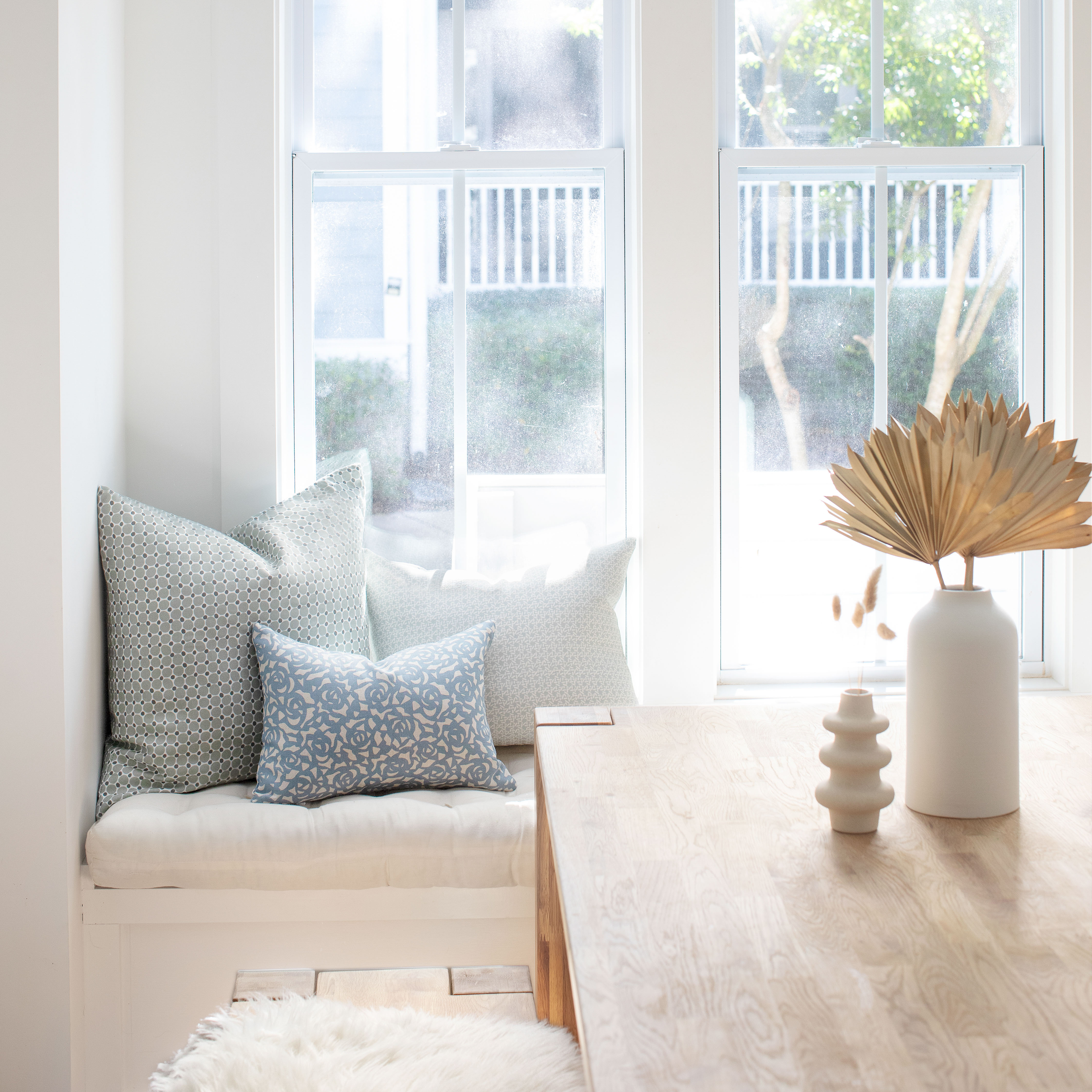 Gardenia pillow in Cobalt styled by Emily Daws – placed on a vintage settee in a Charleston cottage