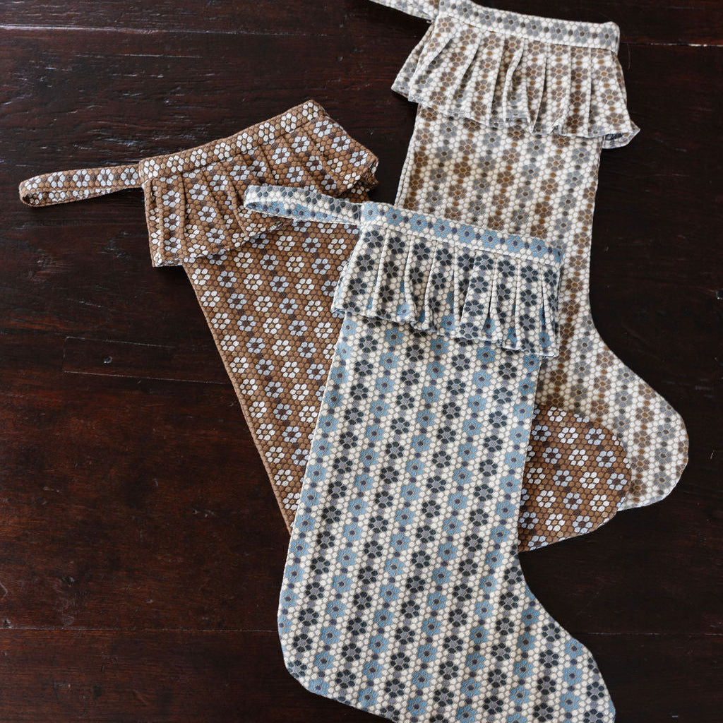 Three Nectar woven fabric stockings by Emily Daws with a pattern on a wooden surface