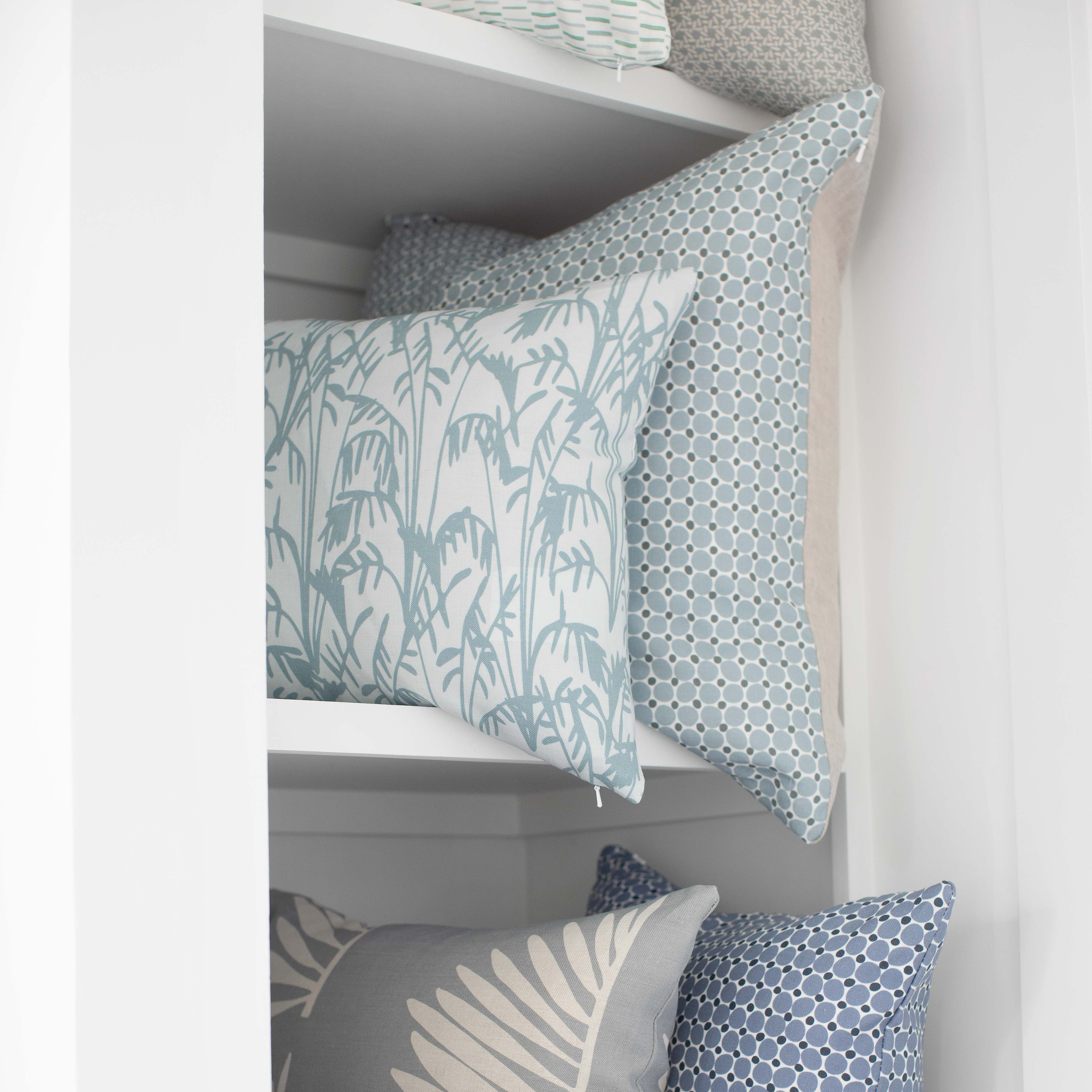 A collection of Emily Daws pillows, stacked and styled with boutique fabrics for layered, storied interiors.