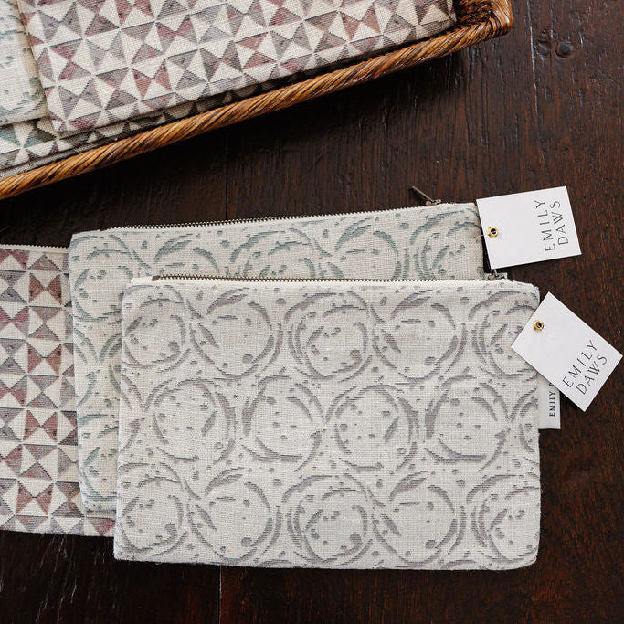 Patterned pouches with Emily Daws brand tags on a wooden surface