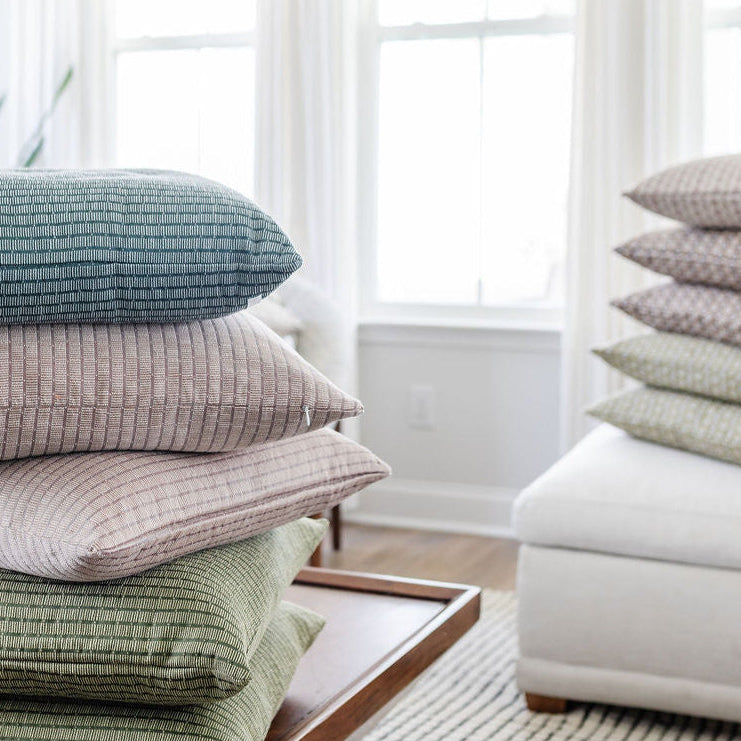 Stack of Emily Daws Jetty Cove pillow stacked in a bright living room, boutique woven textiles designed for Southern-inspired interiors.
