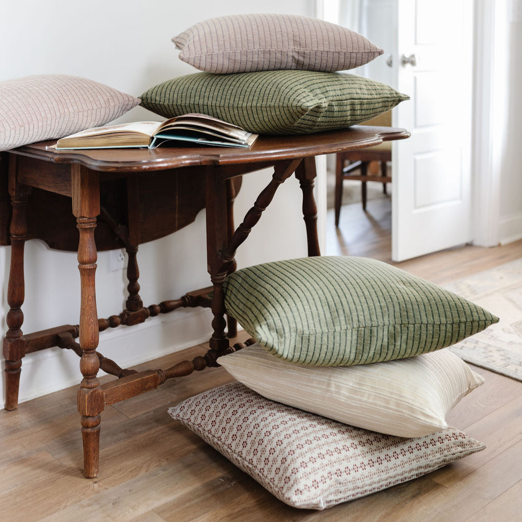 Emily Daws Jetty Palm woven pillows styled in a layered stack, artisanal fabrics offering boutique design options for custom interiors.