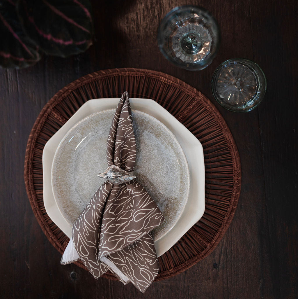 Decorative table setting with a napkin folded into a leaf shape on a wooden surface.