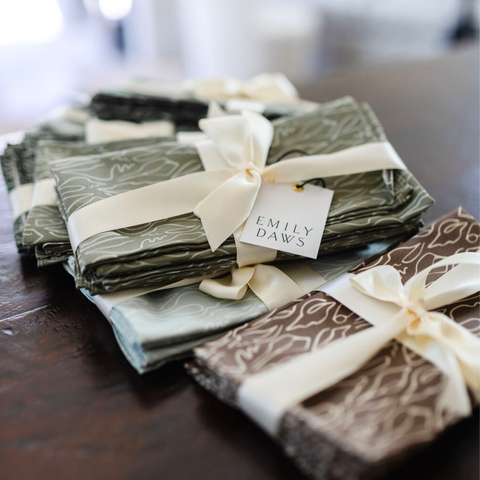 A set of folded cotton sateen dinner napkins in Emily Daws' Little Edisto pattern, tied with white ribbons and labeled 'Little Edisto'.