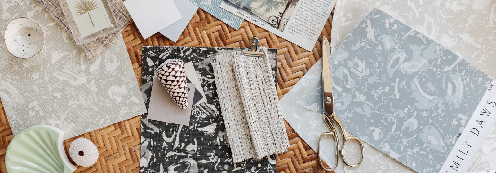 Emily Daws coastal wallpaper samples on a woven rattan table.