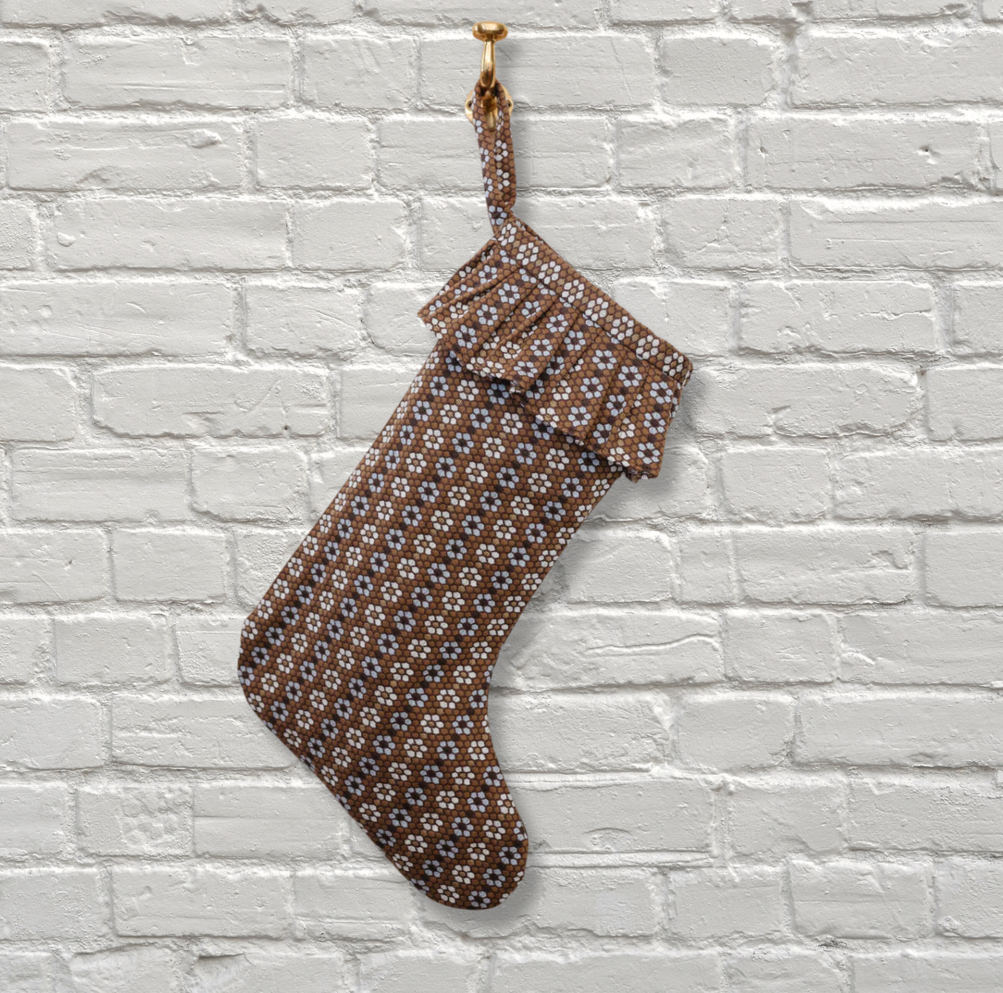 Emily Daws Christmas stocking hanging on a white brick wall.